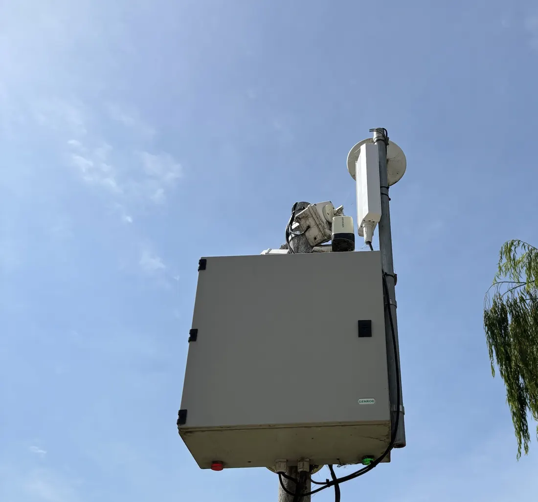 Poste en el parque acuático con un gabinete de equipos y, arriba, un access point exterior, un enlace inalámbrico y una cámara