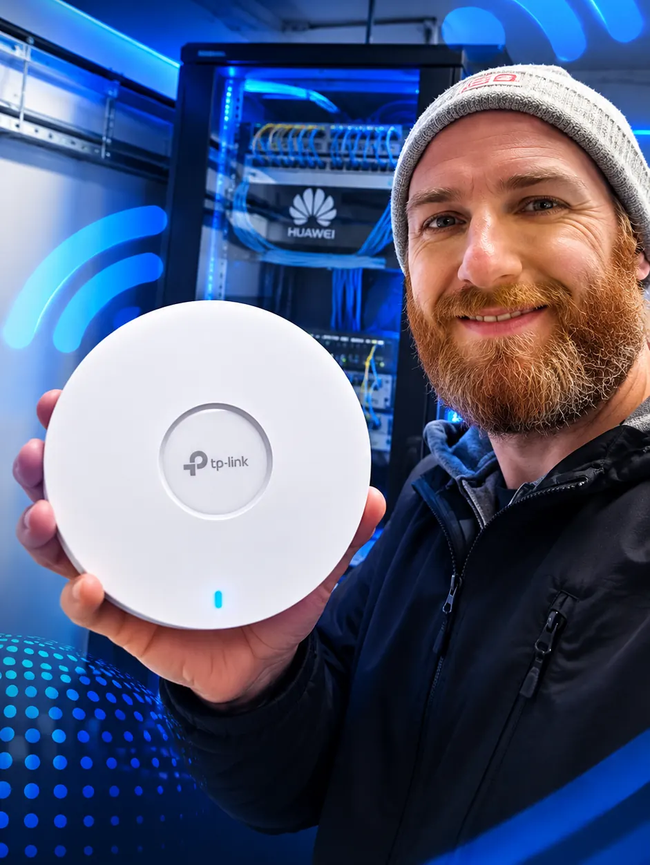 Técnico sosteniendo un access point TP-Link frente a un rack de red